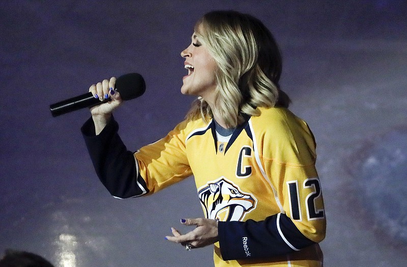 
              FILE - In this April 17, 2017, file photo, country music star Carrie Underwood performs the national anthem before Game 3 of a first-round NHL hockey playoff series between the Predators and the Chicago Blackhawks, in Nashville, Tenn. Underwood is the wife of Predators center Mike Fisher. The town known as Music City has grabbed hold of the Nashville Predators with stars lining up to sing the national anthem or sing with the house band. Reaching the first Western Conference final in franchise history is spreading hockey fever far beyond the arena walls and the team’s loyal fans, sprouting Predators’ flags on front porches with upcoming opponents televised at barbecue joints.  (AP Photo/Mark Humphrey, File)
            