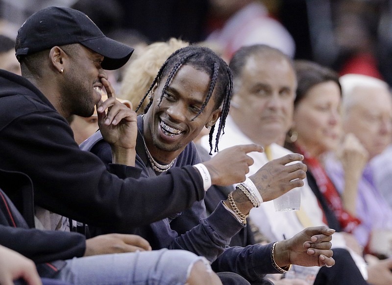 
              FILE - In this April 5, 2017, file photo, rap artist Travis Scott, center, reacts during an NBA basketball game between the Houston Rockets and Denver Nuggets in Houston. Rogers, whose real name is Jacques Webster, was arrested Saturday night May 13, 2017, in Rogers, ark., on charges of inciting a riot, disorderly conduct and endangering the welfare of a minor. Police say Webster encouraged fans to bypass security and rush the stage, leaving a security guard, a police officer and several others injured. (AP Photo/Michael Wyke, File)
            