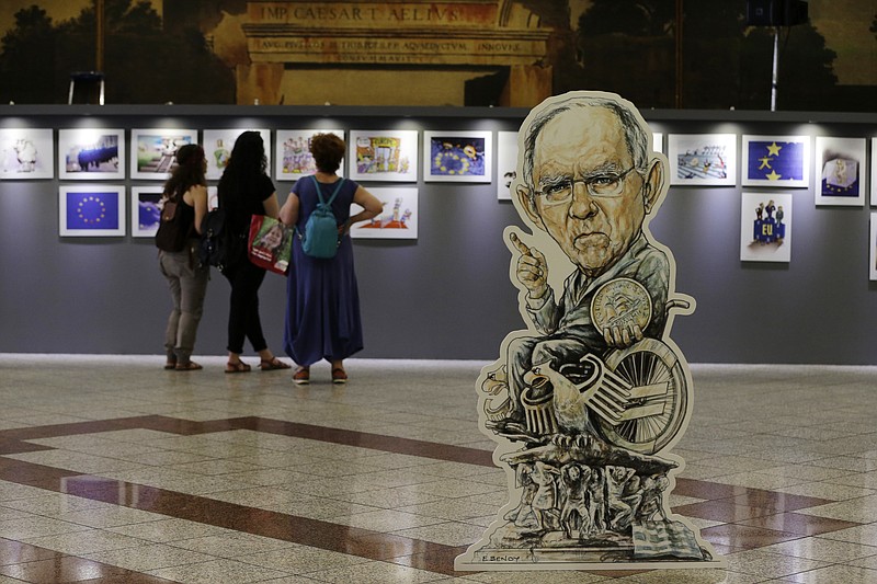 
              An exhibit with the German Finance Minister Wolfgang Schauble holding a Greek drachma coin, is displayed at an exhibition by Greek Cartoonists Association in Athens, Monday, May 15, 2017. Lawmakers in Greece started a four-day debate Monday on whether to approve a new package of spending cuts that will extend the number of years Greeks have lived under austerity to more than a decade. (AP Photo/Thanassis Stavrakis)
            