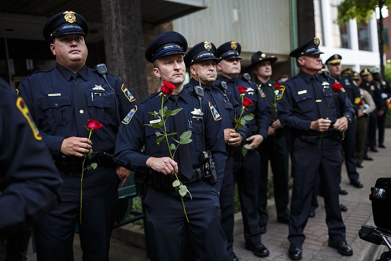 Law enforcement officers hold roses at the 2017 Law Enforcement Memorial Ceremony held at the police memorial statue on Market Street on Thursday, May 18, 2017, in Chattanooga, Tenn. Law enforcement officers from Hamilton County and across the region who lost their lives in the line of duty were honored at the annual ceremony.
