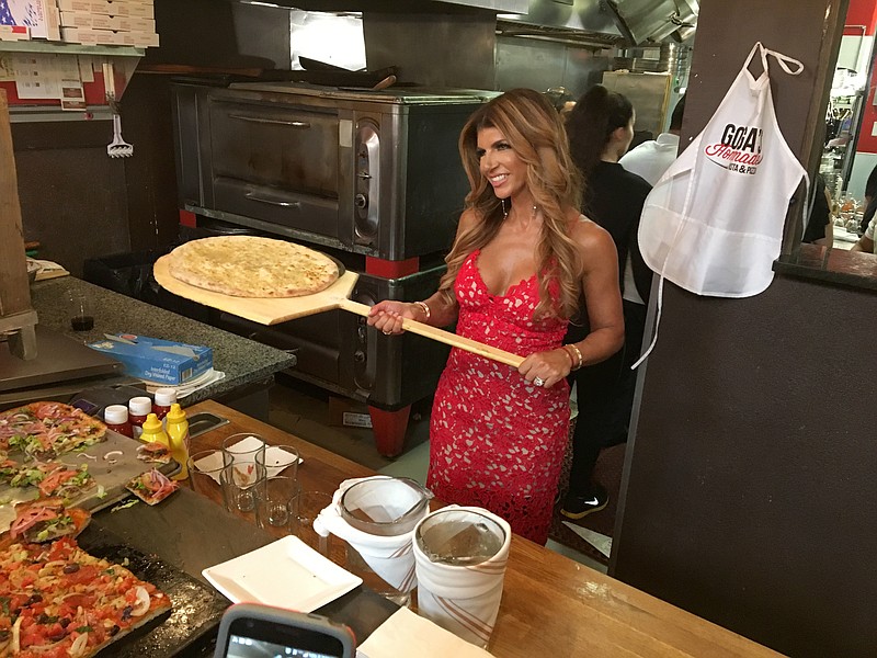 
              In this Thursday, May 18, 2017 photo, "Real Housewives of New Jersey" cast member Teresa Giudice strikes a pose behind the counter at the grand opening of Gorga's Homemade Pasta & Pizza restaurant in East Hanover, N.J.  (Rob Jennings/NJ Advance Media via AP)
            