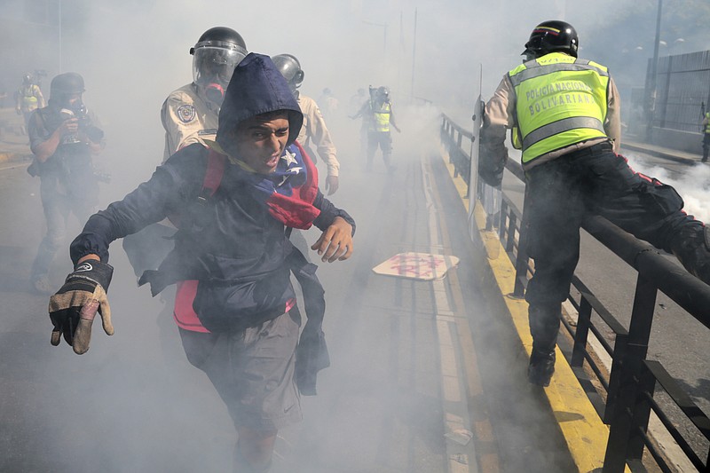 
              A protester tries to flee government security forces during a demonstration by opponents of President Nicolas Maduro who gathered to block a major highway in Caracas, Venezuela, Saturday, May 20, 2017. Tens of thousands of demonstrators took to the streets again in what has been two months of near-daily street protests. Demonstrators are demanding new elections and blaming Maduro for the nation's triple-digit inflation, rising crimes and vast food shortages. (AP Photo/Fernando Llano)
            