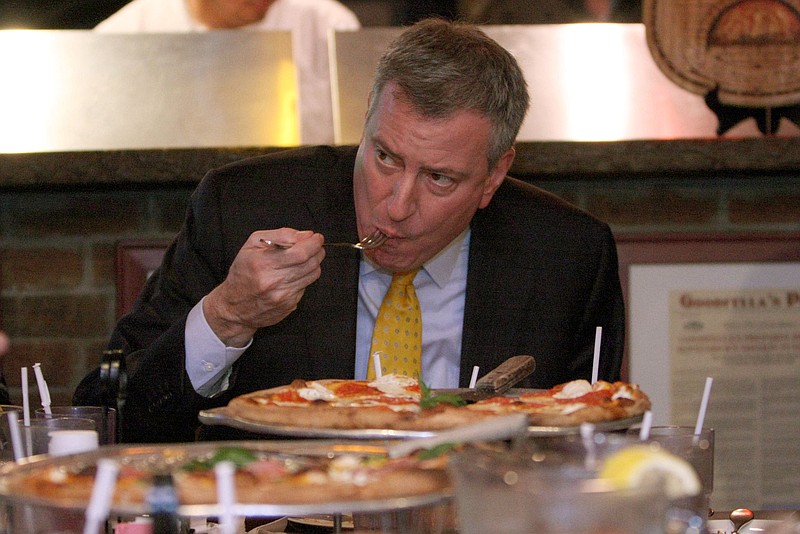 The press office of New York City Mayor Bill de Blasio, who is shown eating pizza, was quick to blame immigration officers recently when fraud investigators came to a local public school, but the incident was completely unrelated to the school district's desire to protect illegal immigrant students.