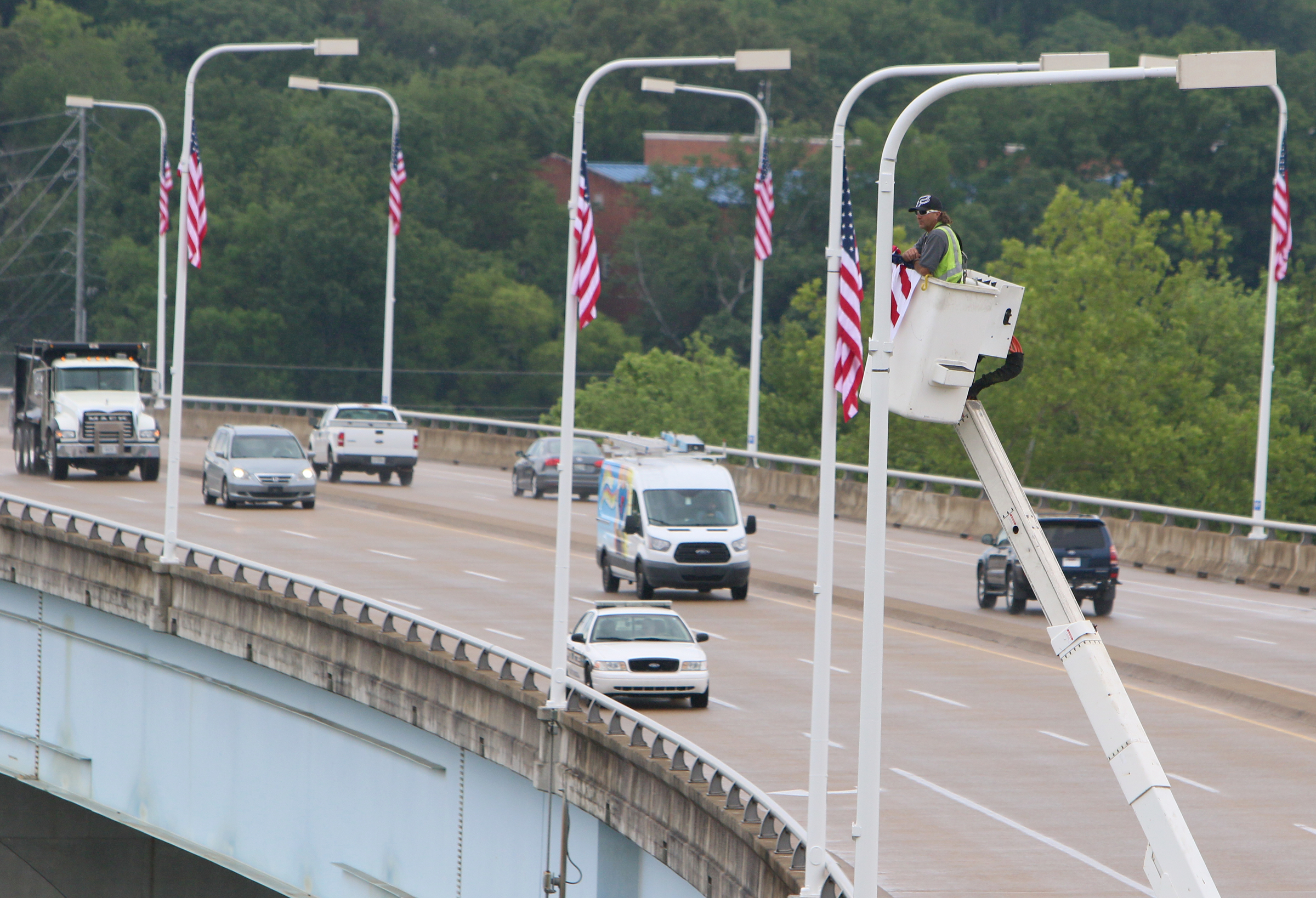 Eddie Poe, a traffic technician with the Chattanooga Department of Transportation, installs the final flag during the Veterans Bridge Flag Raising Ceremony held to honor service men and women Mon., May 22, 2017, at the Bluff View Art District Sculpture Garden in Chattanooga, Tenn. New American flags were raised on Veterans Bridge in honor or memory of loved ones of those who sponsored the flags.