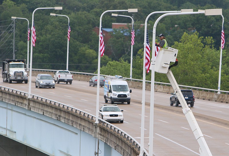 Eddie Poe, a traffic technician with the Chattanooga Department of Transportation, installs the final flag during the Veterans Bridge Flag Raising Ceremony held to honor service men and women Mon., May 22, 2017, at the Bluff View Art District Sculpture Garden in Chattanooga, Tenn. New American flags were raised on Veterans Bridge in honor or memory of loved ones of those who sponsored the flags. 