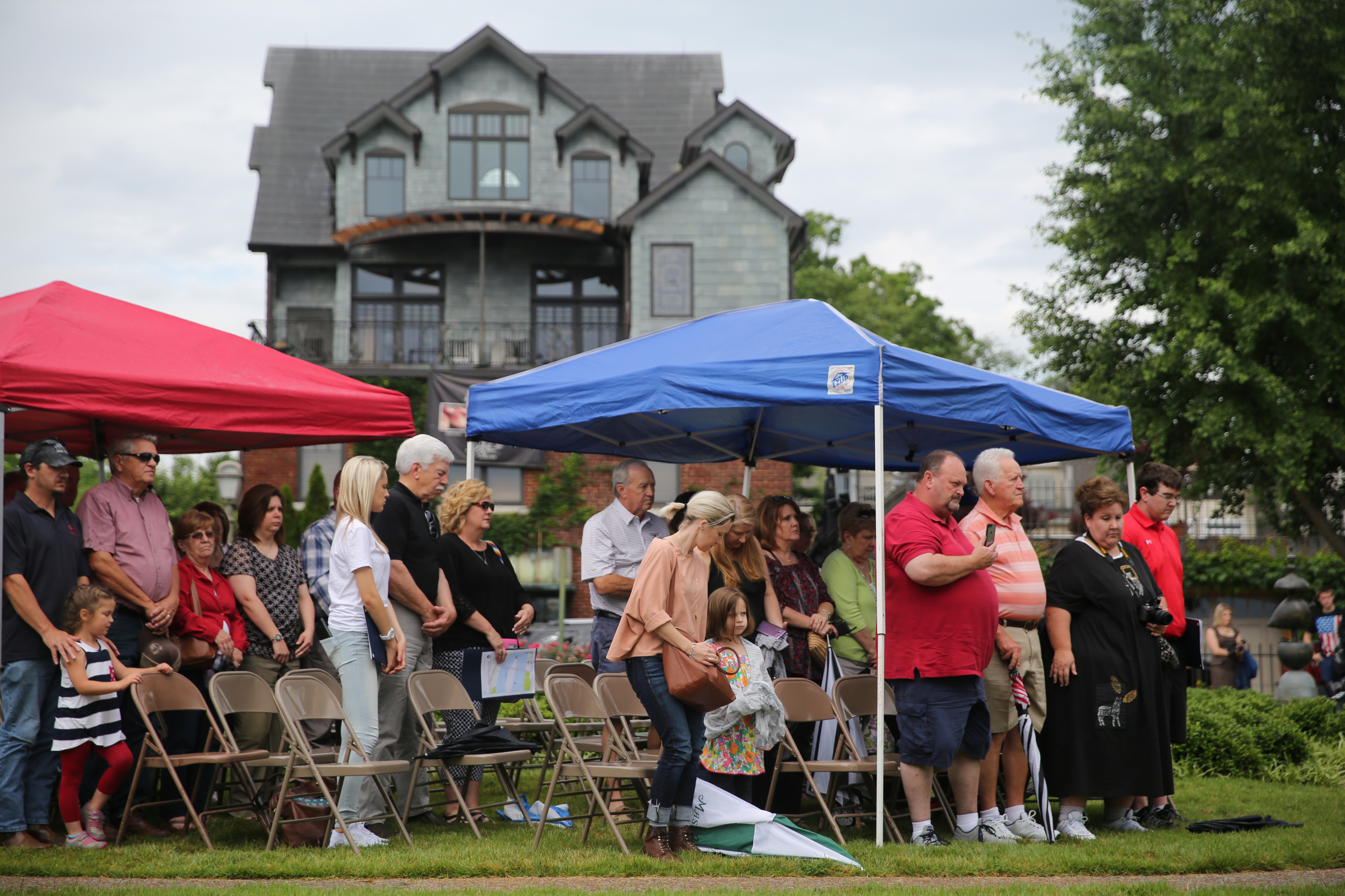 Attendees of the Veterans Bridge Flag Raising Ceremony stand to honor the four marines and sailor killed on July 16, 2015, during the ceremony at the Bluff View Art District Sculpture Garden in Chattanooga, Tenn, on Mon., May 22, 2017. Five flags along Veterans Bridge are permanent installments in memory of the five servicemen.