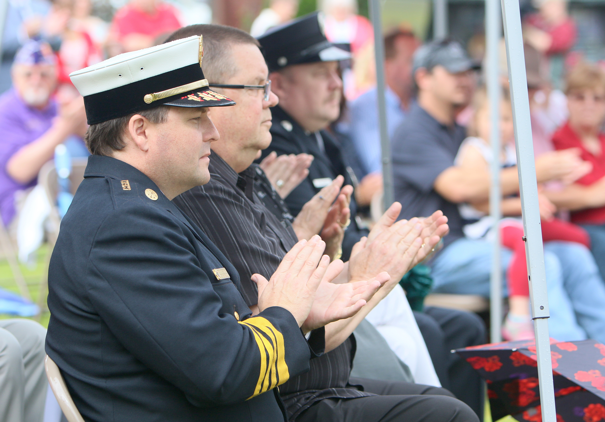 Dep. Chief Seth Miller with the Chattanooga Fire Department and his father Dale Miller clap during a portion of the Veterans Bridge Flag Raising Ceremony held to honor service men and women Mon., May 22, 2017, at the Bluff View Art District Sculpture Garden in Chattanooga, Tenn. Dale was one of the former servicemen honored during the event for his service in the United States Army.