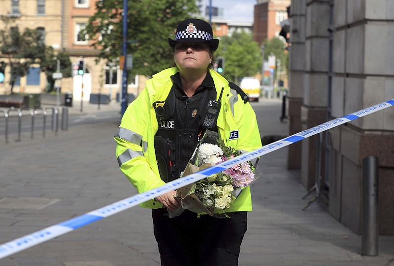 
              A police officer carries a floral tribute close to the Manchester Arena, the morning after a suicide bomber killed more than a dozen people as an explosion tore through fans leaving a pop concert in Manchester England Tuesday May 23, 2017. (Danny Lawson/PA  via AP)
            