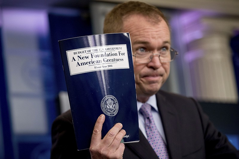 Budget Director Mick Mulvaney holds up a copy of President Donald Trump's proposed fiscal 2018 federal budget as he speaks to members of the media Tuesday. (AP Photo/Andrew Harnik)