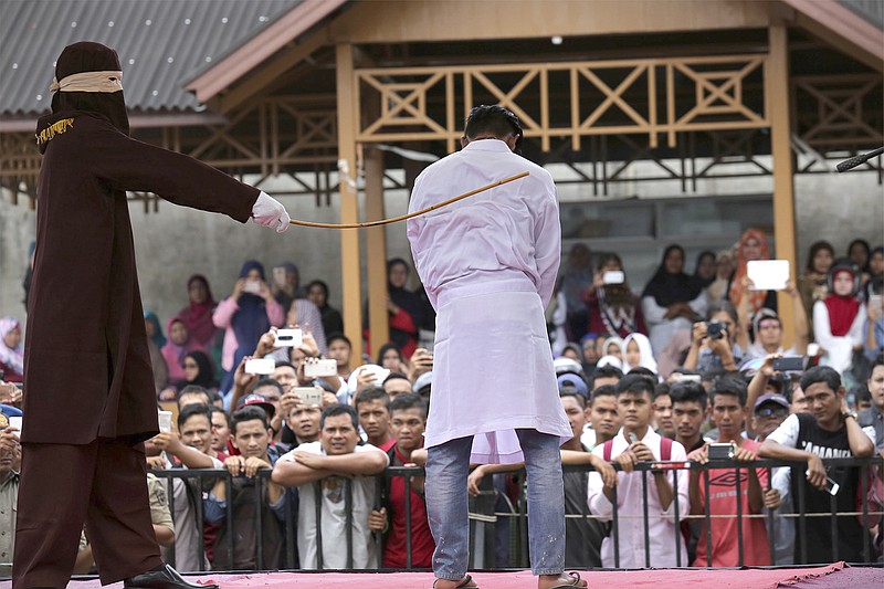 
              FILE - In this Monday, March 20, 2017, file photo, a Sharia law official whips a man convicted of adultery with a rattan cane in Banda Aceh, Indonesia, when two men each face up to 100 stroke of the cane after neighbors reported them to Islamic religious police for having gay sex. Indonesian police detained dozens of men Sunday, May 21 in a weekend raid on a gay sauna in the capital Jakarta, another sign of growing hostility to homosexuality in the world's most populous Muslim nation. (AP Photo/Heri Juanda, File)
            
