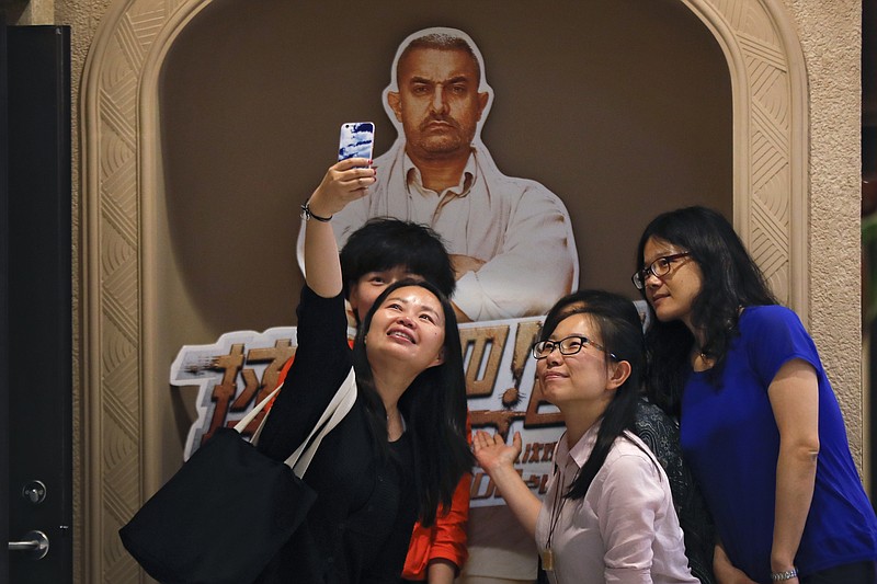 
              In this Monday, May 22, 2017 photo, a group of Chinese women take a selfie with a poster of Indian Bollywood blockbuster film "Dangal" on display at a cinema in Beijing. The Aamir Khan film "Dangal" about an Indian man training his daughters to become wrestlers has become China's biggest grossing non-Hollywood foreign movie. The Indian film was released in China on May 5. By Tuesday, May 23, 2017, the Indian film had pulled in 806 million yuan ($117 million) in mainland China, according to data from EntGroup, a leading entertainment consultant. (AP Photo/Andy Wong)
            