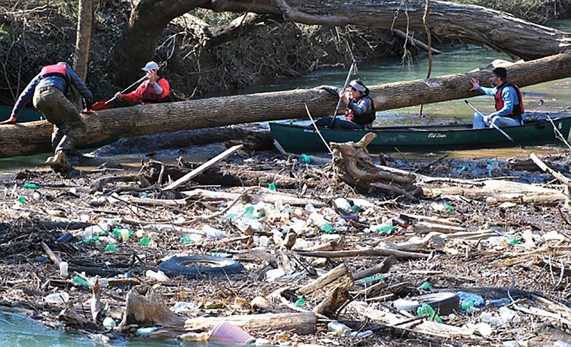 Volunteers cut through downed trees to make a blueway more navigable for paddlers.