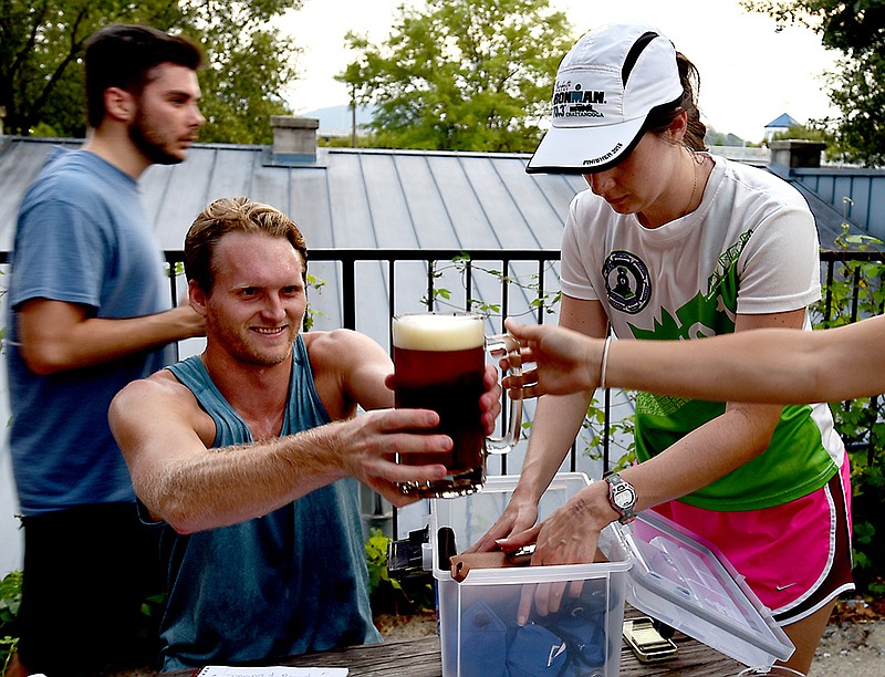 Miller Williams, left, takes his beer as Susanna Kirby retrieves her belongings after the running portion of  "Running for Brews" Wednesday, September 9, 2015, at the Brewhaus.