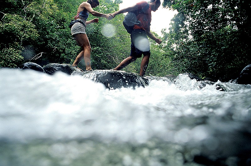 Hikers cross a creek. (Contributed photo by Getty Images)