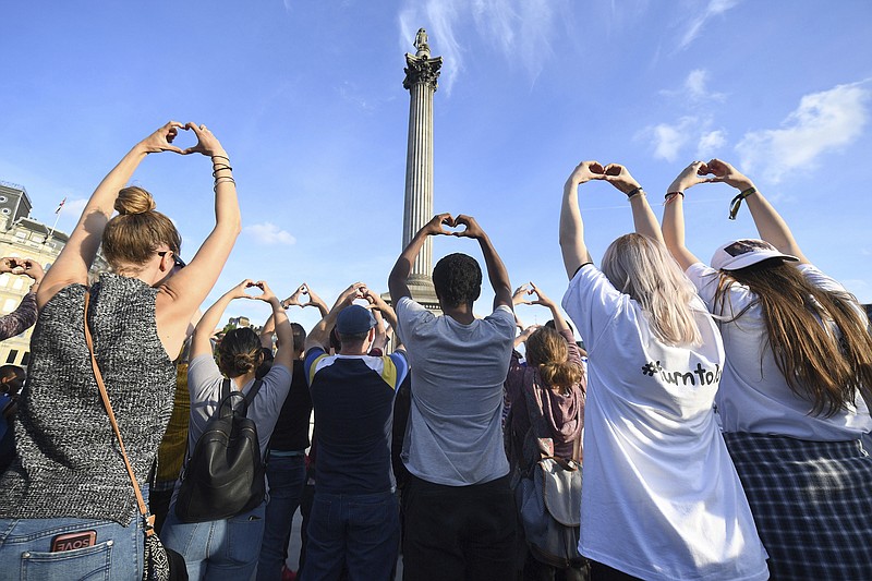 
              People gesture as they attend a vigil in Trafalgar Square, London Tuesday May 23, 2017 for the victims of the attack which killed over 20 people as fans left a pop concert by Ariana Grande in Manchester on Monday night. (Victoria Jones/PA via AP)
            