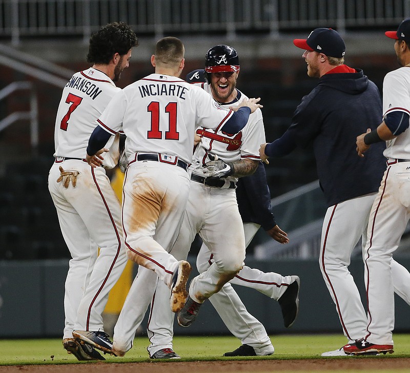 Atlanta Braves first baseman Matt Adams, center, is mobbed by his teammates after driving in the game-winning run with a single in the ninth inning of a baseball game against the Pittsburgh Pirates Wednesday, May 24, 2017, in Atlanta. (AP Photo/John Bazemore)
