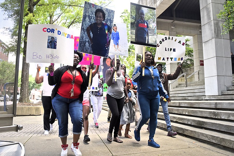 Protestors march on the sidewalk along Market Street in front of the Hamilton County Courts Building.   A march was held downtownon May 25, 2017 to remember the victims of the Woodmore Bus Crash and draw attention to Durham Transportation being retained as the contractor for the county's buses.