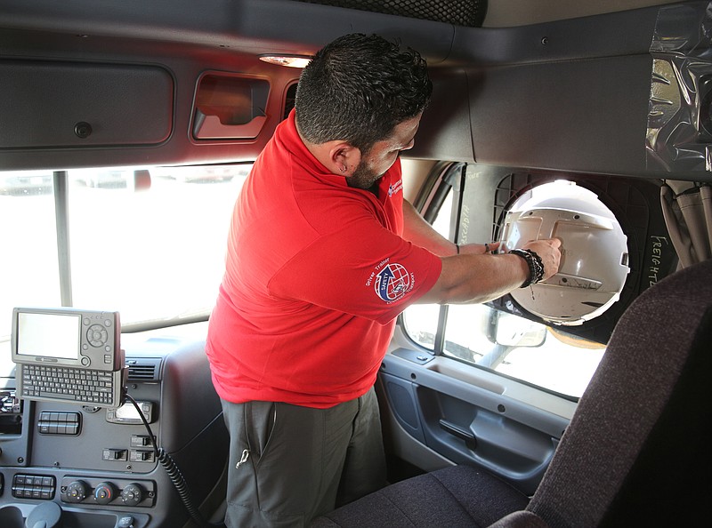 Esteban Torres, master trainer at Covenant Transport, shows how the IdleAir system is installed into the truck window Friday, May 26, 2017, at Covenant Transport in Chattanooga, Tenn. Covenant's IdleAir program recently won a state sustainable transportation award. 