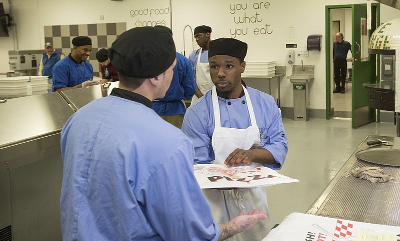
              In this May 23, 2017 photo, inmate Jonathan Scott, right, works in the kitchen at the Cook County Jail in Chicago. Inmates in the jail's medium-security Division 11 are now allowed to order pizzas made by inmates like Scott, who is participating in the jail's "Recipe for Change" program while he waits for trial after his 2015 arrest on an armed robbery charge. in Chicago. (AP Photo/Teresa Crawford)
            