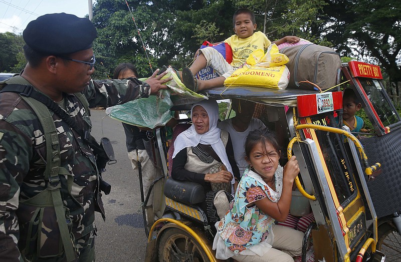 
              Residents fleeing the besieged city of Marawi are questioned at a checkpoint by government soldiers, Friday, May 26, 2017, in Bal-oi township, southern Philippines. Philippine army generals say dozens of Islamic State group-linked extremists have been killed in two days of fighting in a southern city that has been under siege since one of Asia's most-wanted militants evaded capture and dozens of rebels came to his aid. (AP Photo/Bullit Marquez)
            