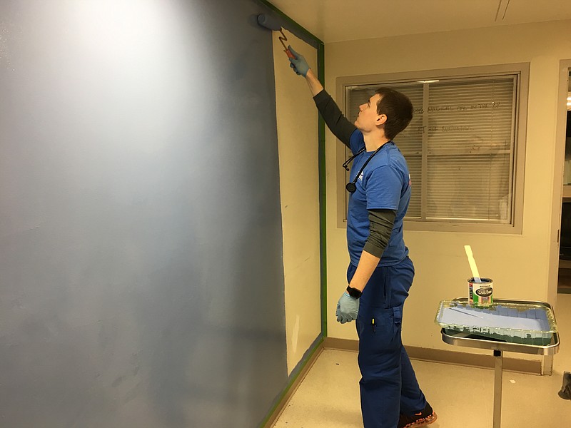 Southern Adventist University student Brian Hustad paints a psychiatry ward holding room with a light blue chalkboard paint to offer patients an opportunity for self-expression.