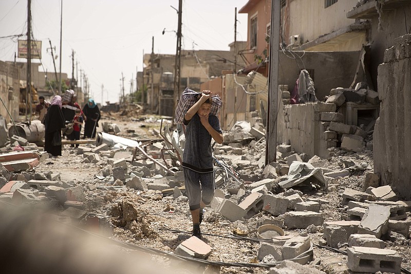 
              FILE - In this May 15, 2017, file photo, an Iraqi boy carries heavy belongings through the rubble as he flees fighting between Iraqi special forces and Islamic State militants, in western Mosul, Iraq. An Iraqi official said a senior Iranian Revolutionary Guard commander was killed in an explosion during clashes with the Islamic State group west of Mosul. Also Saturday, May 27, 2017, aid groups said they are concerned for the safety of civilians following calls from Iraq’s government for residents of the Islamic State-held Old City to flee the area immediately. (AP Photo/Maya Alleruzzo, File)
            