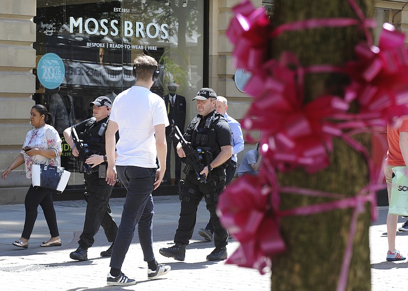 
              Armed police patrol past tribute pink ribbons on a tree in central Manchester, England Friday May 26 2017. More than 20 people were killed in an explosion following a Ariana Grande concert at the Manchester Arena late Monday evening. (AP Photo/Rui Vieira)
            