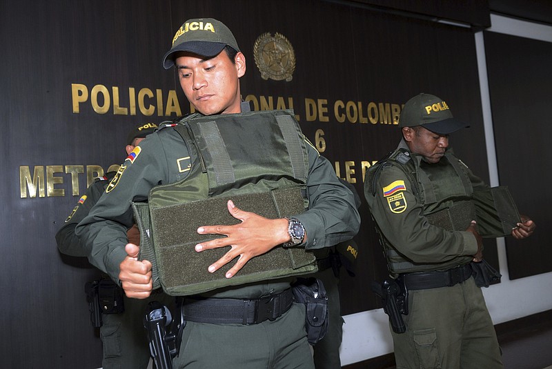 
              Police put on bulletproof vests before leaving a police station to patrol the streets of Medellin, Colombia, Friday, May 26, 2017. In response to Colombia’s largest illegal organization, the Gulf Clan, offering money for people to kill police, the military is sending troops to accompany police and officers are being encouraged to arrive to work in plainclothes, wear bulletproof vests and travel in pairs. (AP Photo/Luis Benavides)
            