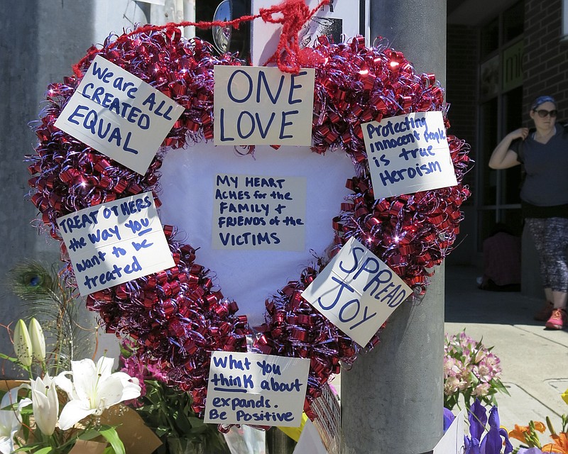 
              A heart-shaped wreath covered with positive messages hangs on a traffic light pole at a memorial for two bystanders who were stabbed to death Friday, while trying to stop a man who was yelling anti-Muslim slurs and acting aggressively toward two young women, including one wearing a Muslim head covering, on a light-trail train in Portland, Ore, Saturday, May 27, 2017. A memorial grew all day Saturday outside the transit center in Portland, as people stopped with flowers, candles, signs and painted rocks. Jeremy Joseph Christian, 35, was booked on suspicion of murder and attempted murder in the attack. (AP Photo/Gillian Flaccus)
            