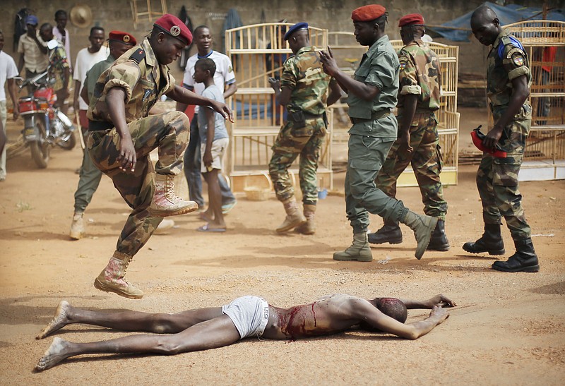 
              In this Wednesday Feb. 5, 2014 photo, a FACA (Central African Armed Forces) officer jumps on the lifeless body of a suspected Muslim Seleka militiaman moments after Central African Republic Interim President Catherine Samba-Panza addressed the troops in Bangui, Central African Republic. A sweeping United Nations report has identified hundreds of human rights violations in Central African Republic that may amount to war crimes. The Tuesday may 30, 2017, report comes amid growing fears that the country terrorized by multiple armed groups is once again slipping into the sectarian bloodshed that left thousands dead between late 2013 and 2015.  (AP Photo/Jerome Delay-File)
            