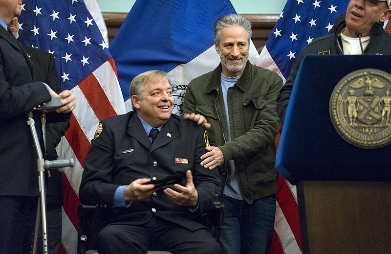 
              FILE- In this Jan. 9, 2016 file photo, comedian Jon Stewart, right, pats the shoulders of retired FDNY firefighter and Sept. 11 first responder Ray Pfeifer after Pfeifer was given the key to the city at New York's City Hall. Stewart fought back tears Friday, June 2, 2017, during Pfeifer's funeral, as he described his friendship with the retired New York City firefighter who worked in the rescue effort following the Sept. 11 terror attacks. (AP Photo/Craig Ruttle, File)
            