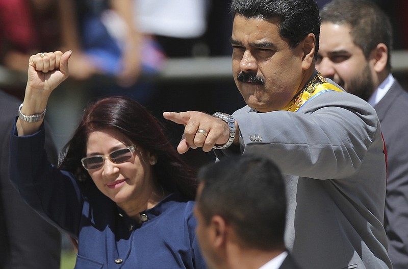 
              FILE - In this Feb. 1, 2017 file photo, Venezuela's President Nicolas Maduro, right, and first lady Cilia Flores greet supporters upon arrival to a military parade at Fort Tiuna in Caracas, Venezuela. On Thursday, June 1, 2017, Maduro called on his wife and other heavyweights in the ruling socialist party to lead the government's campaign to rewrite the constitution. (AP Photo/Fernando Llano, File)
            