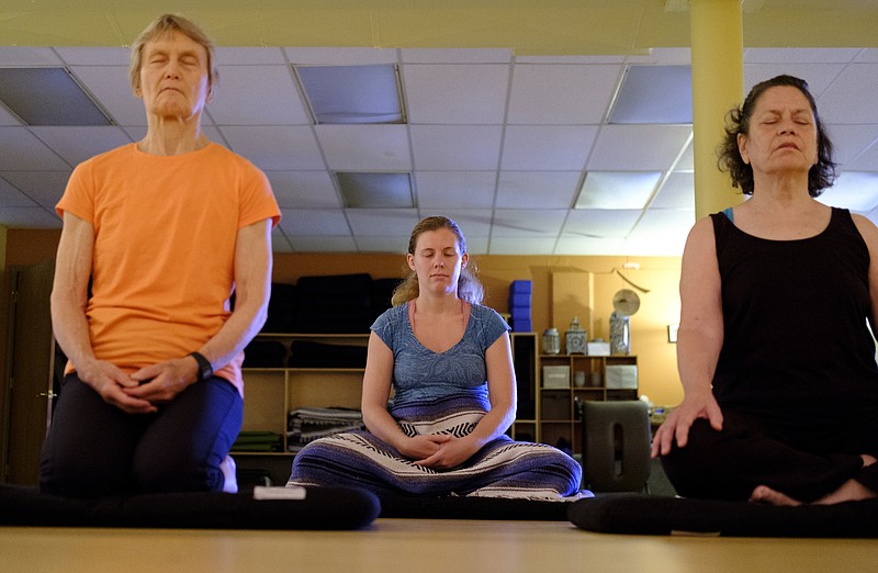 Staff photo by Doug Strickland / Susan Corn, Rachel Kaufman, and Fran Randall, from left, participate in a meditation class at Clearspring Yoga on Wednesday, May 11, 2016, in Chattanooga, Tenn. Meditation is an important activity in Buddhism that helps to promote behaviors that are central to its teachings.