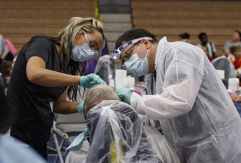 RDA Chelsey Mangum, left, and Dr. Nick Makrides work on a patient's teeth during a Remote Area Medical treatment day at Red Bank High School on Saturday, June 3, 2017, in Chattanooga, Tenn. Remote Area Medical provides mobile medical clinics which deliver free care to underserved communities.
