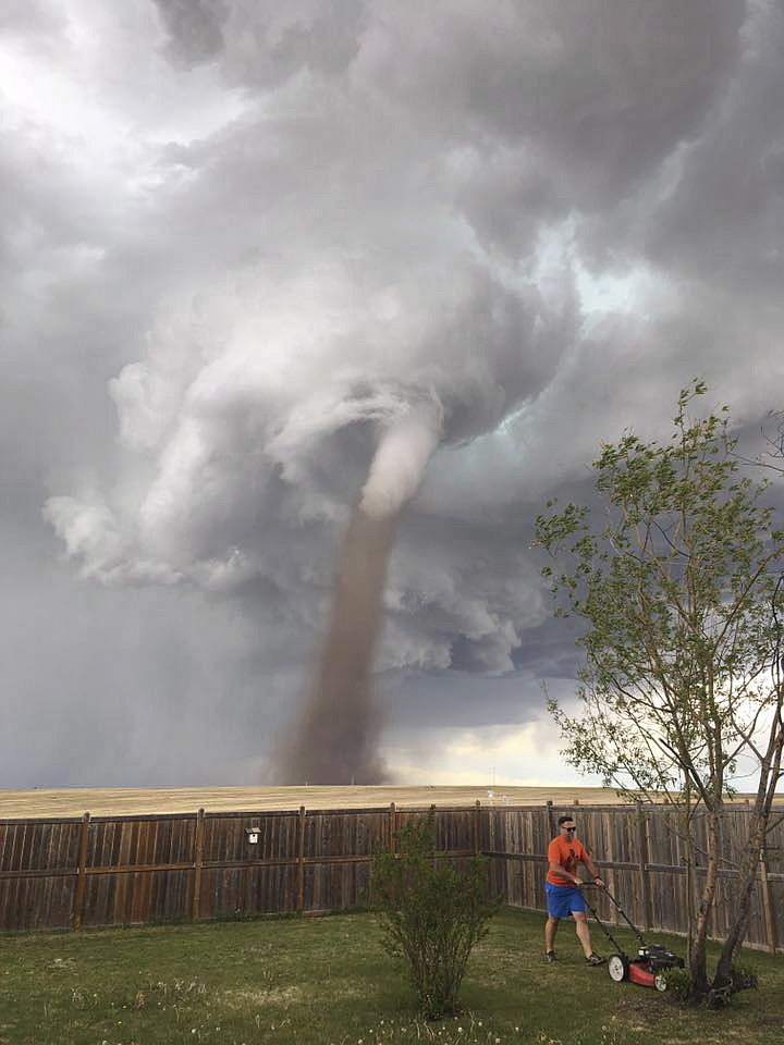 
              In this Friday, June 2, 2017, photo provided by Cecilia Wessels via The Canadian Press, Theunis Wessels mows his lawn at his home in Three Hills, Alberta, as a tornado swirls in the background. Cecilia Wessels, who took the image of her husband to show the tornado to her parents in South Africa, said that the twister wasn't as close it appears. (Cecilia Wessels/The Canadian Press via AP)
            