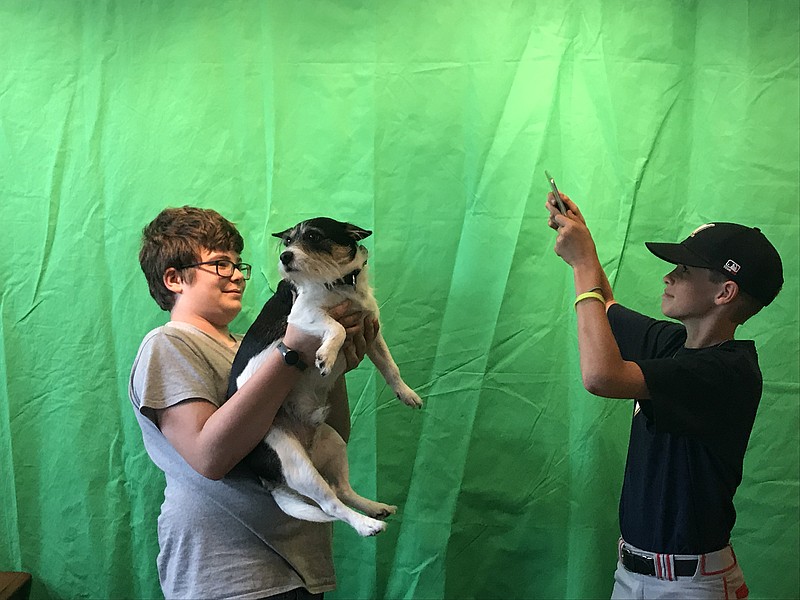 Luke Anderson, left, holds dog Kenny Anderson as Luke Bell films. Kids participating in the Documentary Film or Animation Green Screen camps this summer at the MACC will learn to use their devices to create short films. (Staff photo by Emily Crisman)