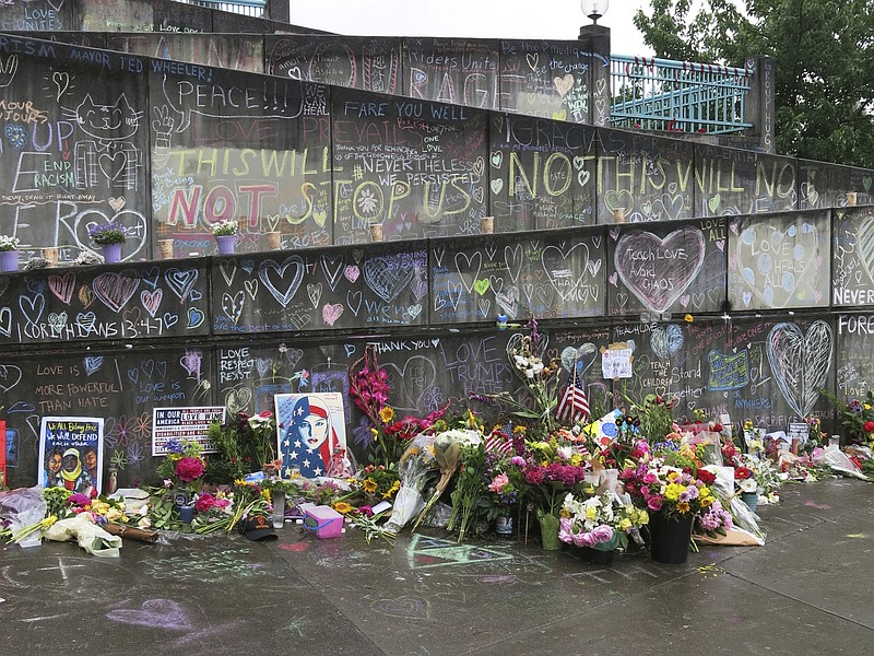 Flowers, candles and chalk tributes covered a memorial last week to two men who were fatally stabbed after shielding two young women from an anti-Muslim tirade on a Portland, Ore., light-rail train. Jeremy Joseph Christian, 35, is charged with aggravated murder and attempted murder. (AP Photo/Gillian Flaccus)