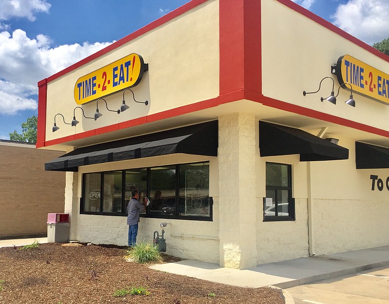 Grady Williams, one of the owners of the new Time-2-Eat! restaurant, washes the front window of the Brainerd Road eatery, which will open on Monday.