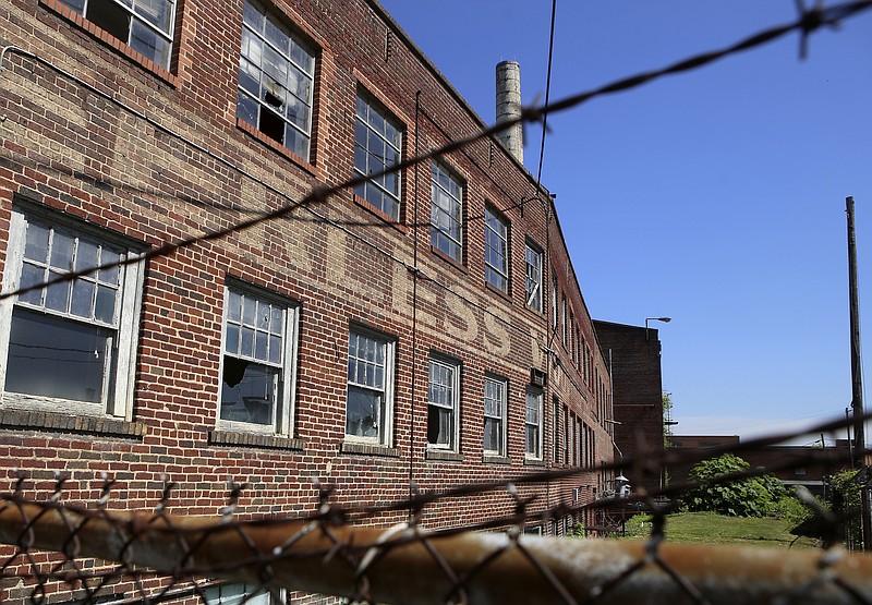 Staff photo by C.B. Schmelter / Peerless Woolen Mills is seen through the barbed wire of one of its fences on Friday, June 9, in Rossville, Ga.