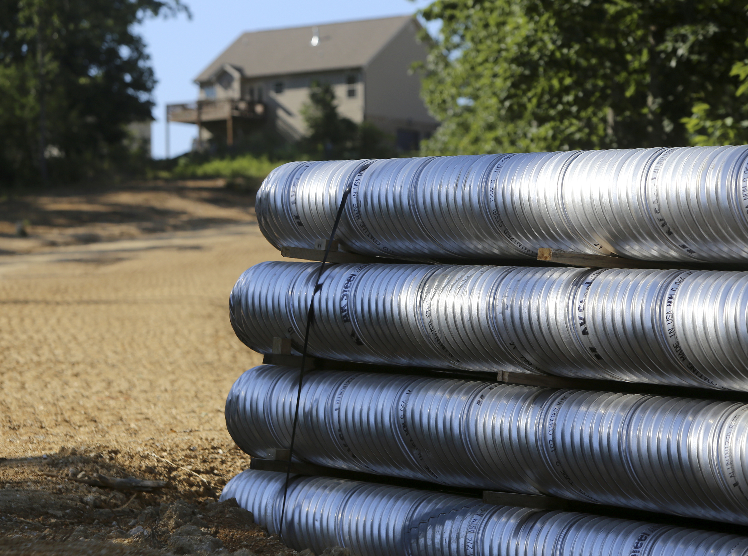 Piping sits behind a completed home in the Hamilton on Hunter subdivision on Friday, June 9, in Harrison, Tenn.