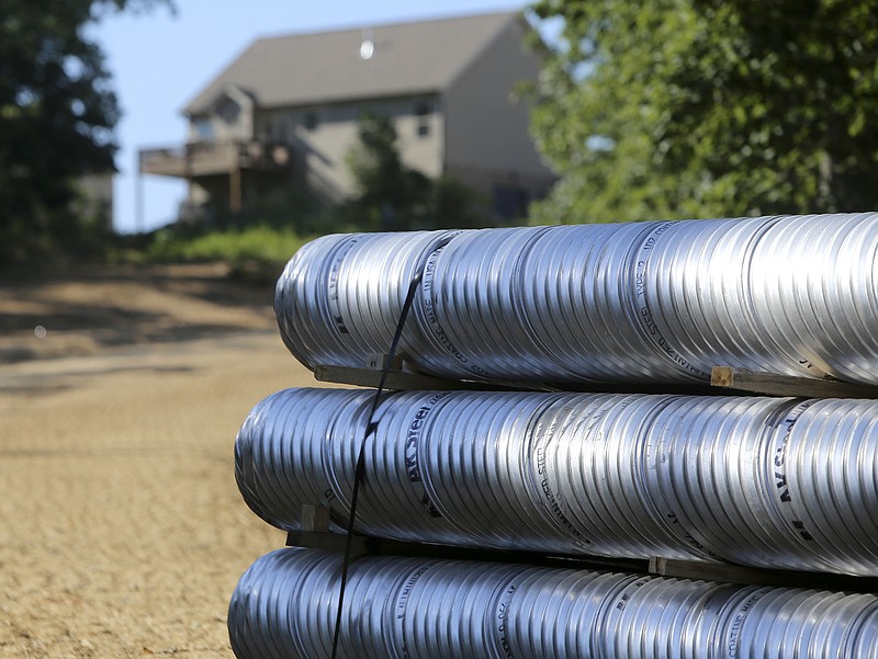 Piping sits behind a completed home in the Hamilton on Hunter subdivision on Friday, June 9, in Harrison, Tenn.