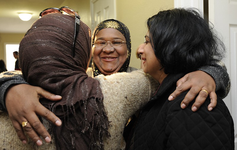 Staff photo by Jenna Walker/Chattanooga Times Free Press - Feb 5, 2011 -- Fatmeh Abobaker, middle, hugs Zainab Shafi, left, and Sheema Azhar, right, during the dedication of the completed Abobaker/Zain Habitat for Humanity home in Chattanooga, Tenn.  The Abobaker/Zain family escaped from the tribal wars in Somalia and were brought to America with assistance of Bridge Refugee Services and the local muslim community.