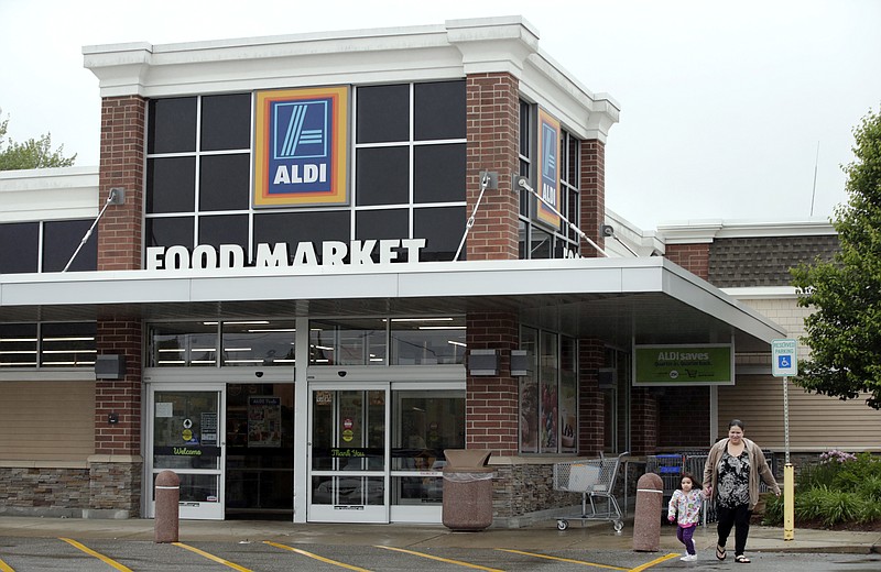 In this June 5, 2017, photo, a woman and child walk from Aldi food market, in Salem, N.H. Low-cost grocery chain Aldi says it plans to add more stores in the U.S. over the next five years, meaning more competition for traditional grocers, Walmart and organics-focused chains like Whole Foods. (AP Photo/Elise Amendola)