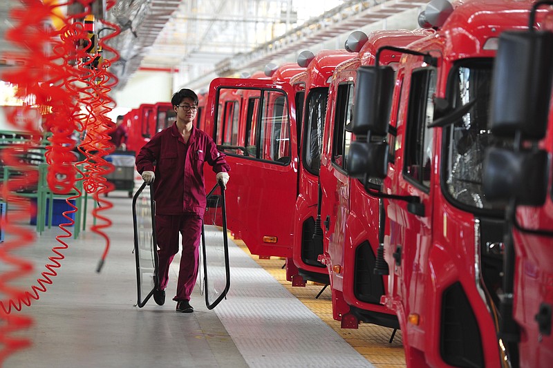 
              In this April 17, 2017 photo, a worker carries glass panels as he works along a truck assembly line at an automotive plant in Fuyang in central China's Anhui province. China’s auto sales shrank for a second month in May amid weak demand following a rise in sales tax, an industry group reported Monday, June 12.
 (Chinatopix via AP)
            
