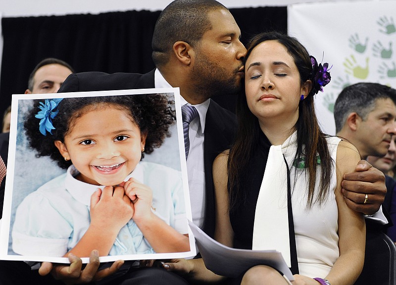 
              FILE - In this Jan. 14, 2013, file photo, Jimmy Greene, left, kisses his wife Nelba Marquez-Greene while holding a portrait of their daughter, Sandy Hook Elementary School shooting victim Ana Marquez-Greene, at a news conference at Edmond Town Hall in Newtown, Conn. Ana Marquez-Greene was one of 26 people killed in a shooting massacre at the school on Dec. 14, 2012, in Newtown, Conn. Nelba Marquez-Greene is among the families of some shooting victims angered by a planned NBC television interview by Megyn Kelly scheduled to air Sunday, June 18, 2017, with Alex Jones, who has claimed the 2012 massacre never happened. (AP Photo/Jessica Hill, File)
            