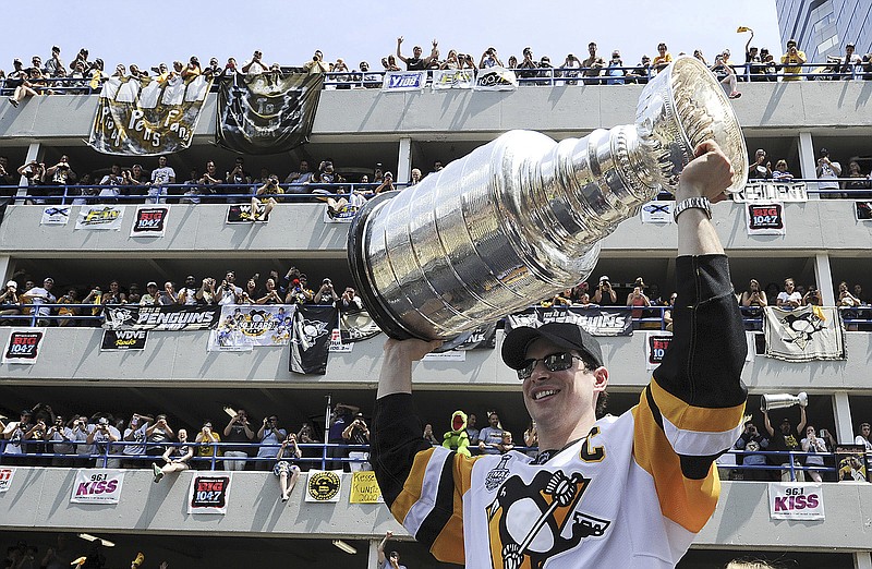 
              Sidney Crosby raises the Stanley Cup on the Boulevard of the Allies in Pittsburgh, in front of a parking garage packed with jubilant fans, on Wednesday, June 14, 2017, during the Pittsburgh Penguins' victory parade and rally. (Lake Fong/Pittsburgh Post-Gazette via AP)
            