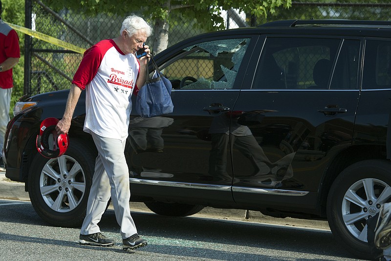 Rep. Jack Bergman, R-Mich. talks on the phone while walking past a damaged vehicle at a shooting scene where House Majority Whip Steve Scalise of La. was shot at a Congressional baseball practice, Wednesday, June 14, 2017, in Alexandria, Va. (AP Photo/Cliff Owen)

