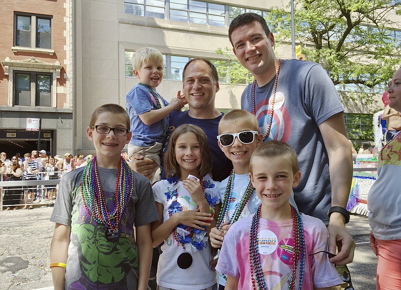 
              ADVANCE FOR USE SUNDAY, JUNE 18, 2017 AND THEREAFTER-This June 26, 2016 photo provided by the family shows Kevin Neubert, background center, and Jim Gorey with their adopted children, from left, Luke, Derek, Natalie, Zach, and Jacob at the Chicago Pride Parade. Following night classes to qualify as foster parents, Neubert and Gorey agreed in December 2011 to provide a temporary home for a newborn baby. A stay intended to last only for a few days was extended into several months, and Neubert and Gorey learned that the baby had four older siblings who were also in foster care. They eventually decided to adopt all five. (Nicole Gifford Baugh/Jim Gorey via AP)
            