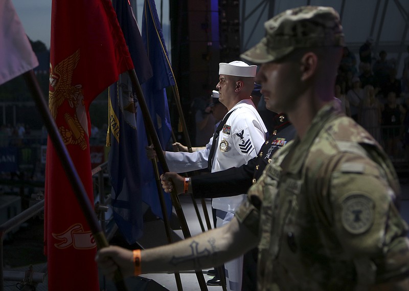 Navy Counselor 1 Rob Molloy holds the Navy flag on the Coke Stage during the playing of Taps during Military Appreciation Night at the Riverbend Festival at Ross's Landing on Friday, June 16, in Chattanooga, Tenn. Country star Toby Keith headlined the evening.