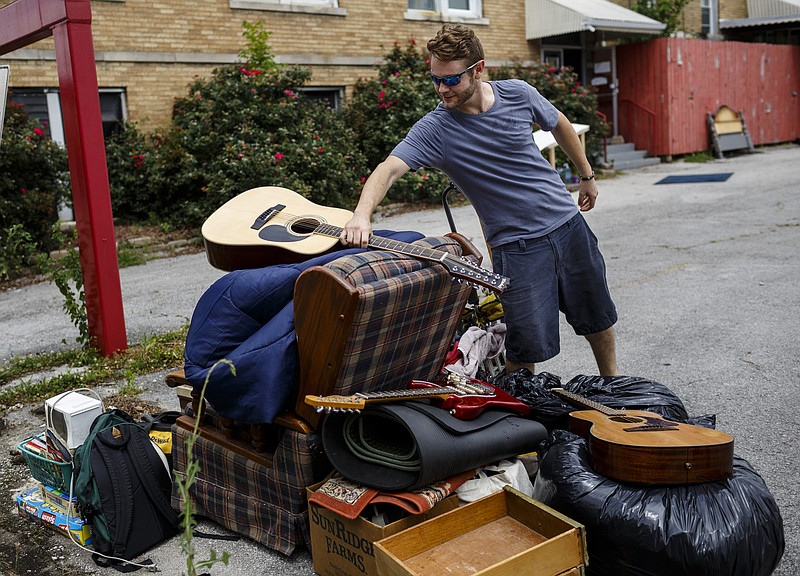 Tyler Short places a guitar on top of a pile of his belongings outside Mercy Junction Justice and Peace Center in Highland Park after his eviction on Friday, June 16, 2017, in Chattanooga, Tenn. Short is one of two occupants who rented space in the building and started the Church of Urth who were evicted after threatening behavior which resulted in the shutdown the center's ministries for more than a month.